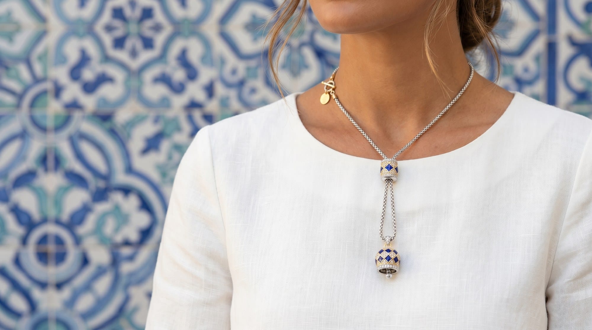 Donna con collana lariat doppia campanella blu su sfondo azulejo