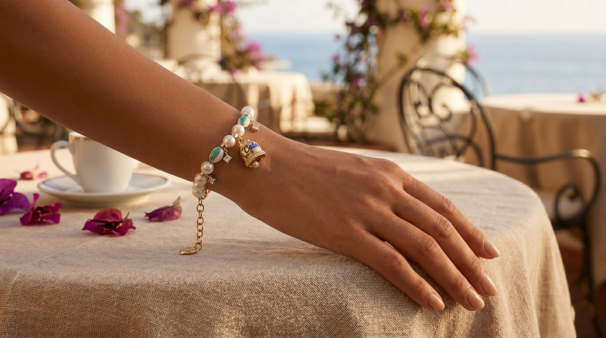 Bracciale charm campanelle su tavolo con bouganville